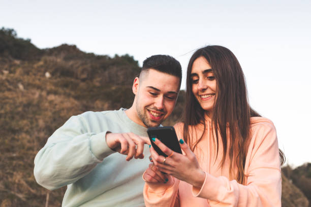 istock Young caucasian couple using a smartphone on the nature. 1369088602