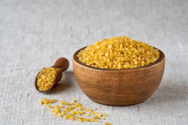 Uncooked bulgur in wooden bowl on linen cloth background. Bulgur wheat grains .Closeup Food , Dry , Bulgur bulgur wheat stock pictures, royalty-free photos & images