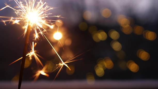 Sparkler firework burning on window, New Year or Christmas bengal lights. Winter Xmas holiday celebration magic, sparkles, golden garland and fire stars light glowing. Seamless looped cinemagraph.