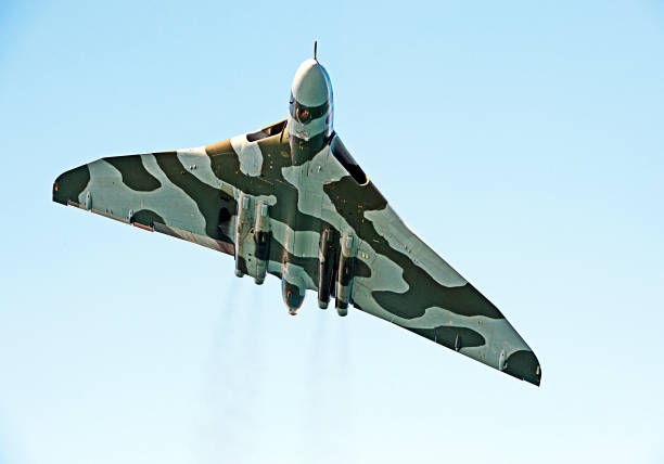 Vulcan nuclear bomber in flight over English Channel, England. Avro Vulcan cold war nuclear delta wing bomber airplane in camouflage flying over Poole Bay, English Channel in blue clear sky
