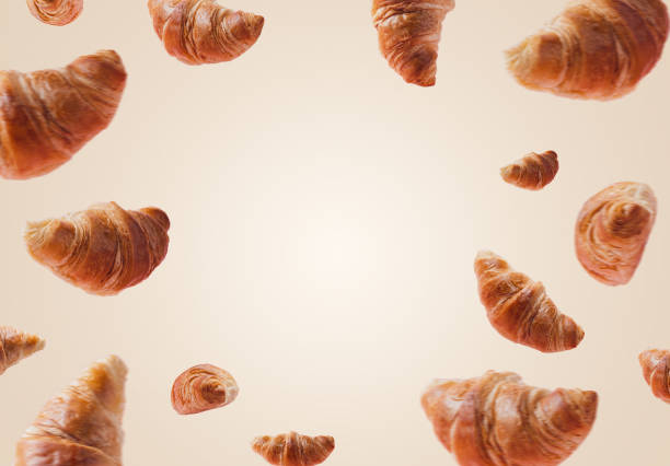 Croissants levitating or flying on white beige background. Levitation, fly scene