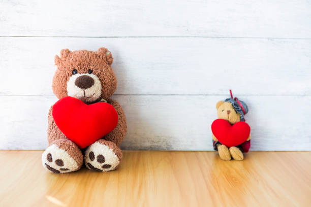 istock Old teddy bear holding red heart sitting with blurred background 1369093161