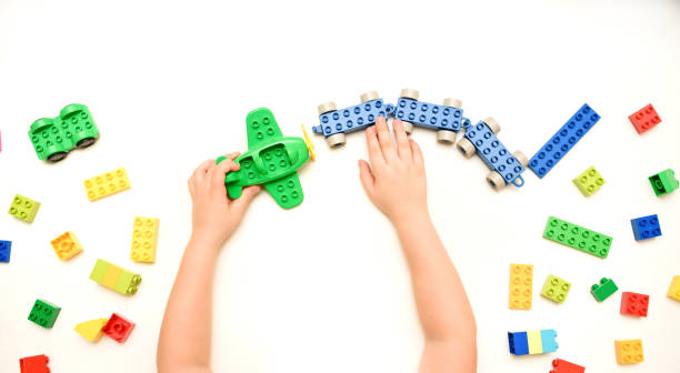 istock Close up kid boy hands playing with toy airplane and toy bricks  on white background. 1369095691