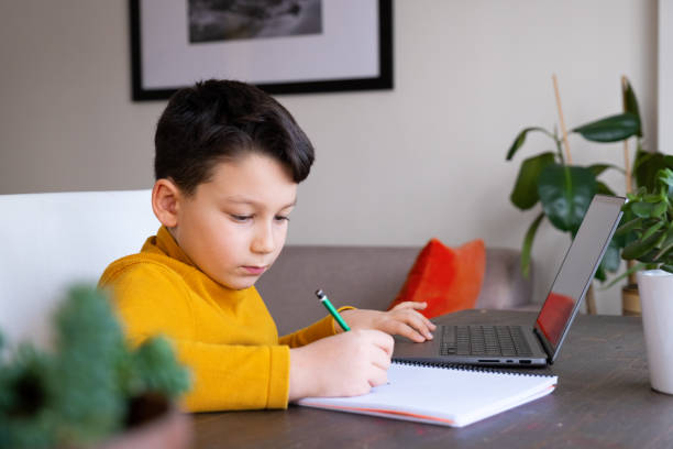 istock 8-9 years cute child using laptop. Learning at home. 1369096044
