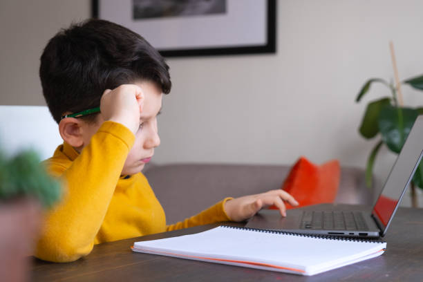 istock 8-9 years cute child using laptop. Learning at home. 1369096079