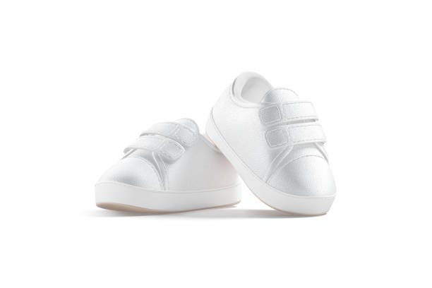Blank white baby shoes pair mockup on tiptoe, half-turned view, 3d renderig. Empty slip-on sneakers for infant or toddler mock up, isolated. Clear small gumshoes for kid sport outfit template.