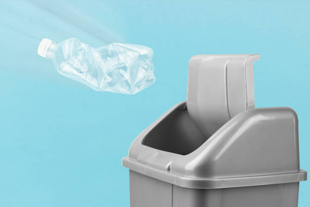 istock Throw a plastic bottle into the trash can, gray bucket on a blue background, plastic recycling concept 1369097472