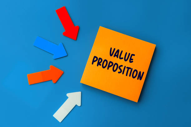 istock Value Proposition - concept of text on sticky note. Orange square sticky note and colorful arrows on blue background, top view 1369098343