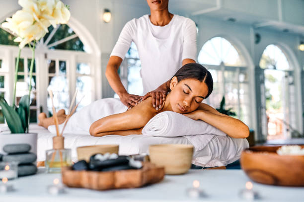 Shot of an attractive young woman lying on a bed and enjoying a massage at the spa She knows exactly where all my tension lives massaging stock pictures, royalty-free photos & images