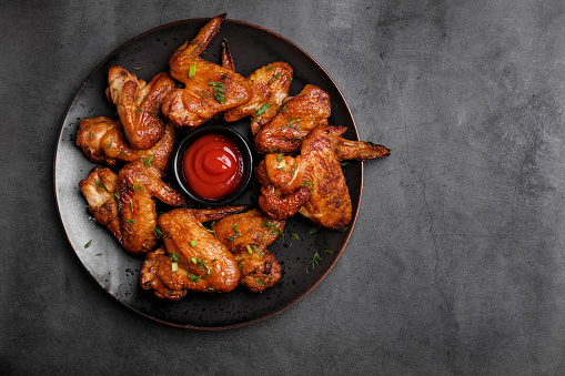 Plate of barbecue chicken wings with sauce. Close up and top view