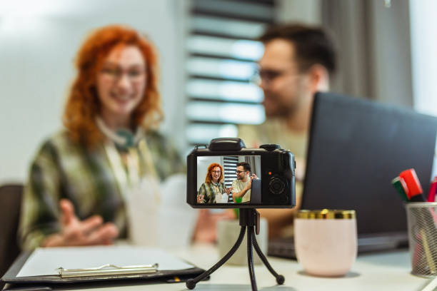 istock Couple of bloggers broadcasting from home, using camera. 1369101682