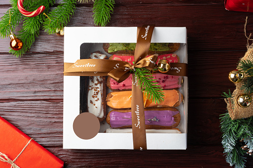 Box of colorful eclairs on Christmas background, close up