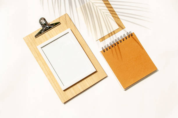 istock Mockup with blank notepads and frame on white background. Contrasting shadows concept. View from above 1369104431