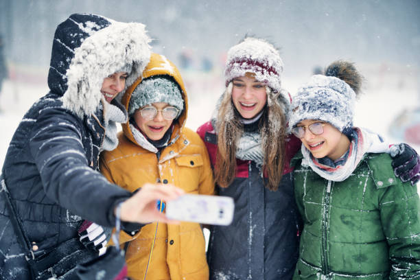 video ritratto di madre e tre bambini che scattano selfie durante la bufera di neve - group of people teenager snow winter foto e immagini stock