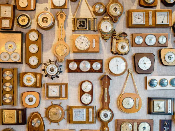collection of retro old barometers and watches hanging on a textured wall