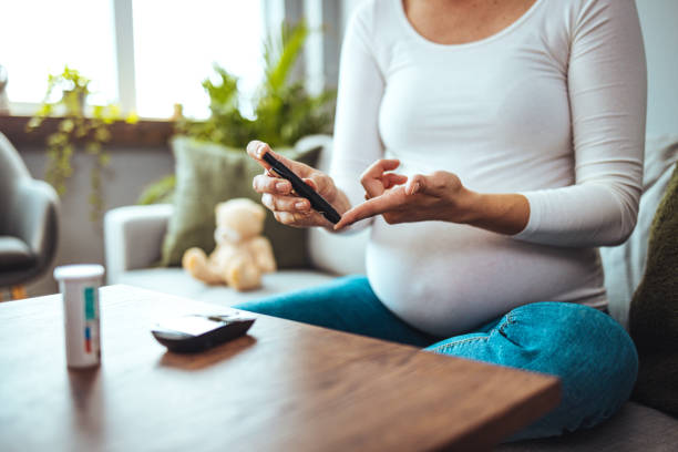 Happy Pregnant woman with glucometer checking blood sugar level at home. Happy Pregnant woman with glucometer checking blood sugar level at home. Woman testing for high blood sugar. Pregnant Woman holding device for measuring blood sugar glucose photos stock pictures, royalty-free photos & images