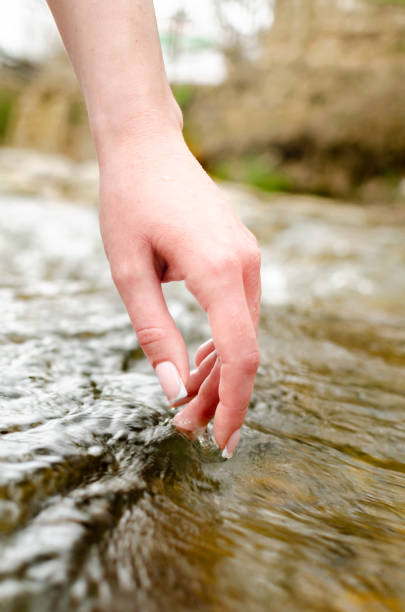 istock hand touches the water of a mountain river 1369106952
