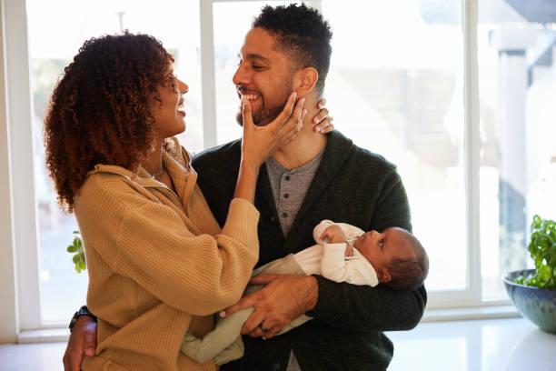 istock Affectionate couple smiling while standing with their baby boy at home 1369109790