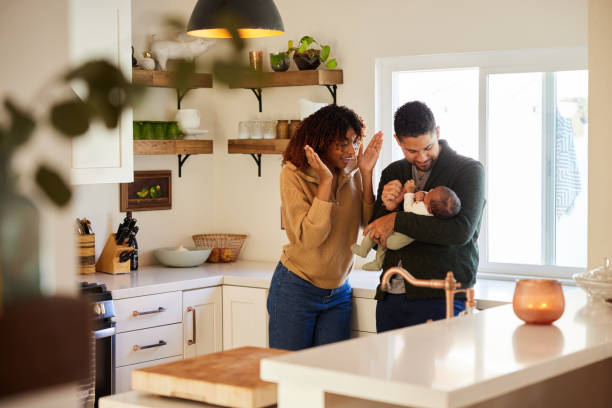 Smiling parents playing peekaboo with their baby boy at home stock photo