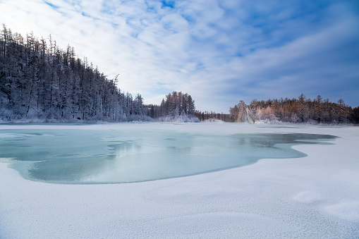 Frozen bay of Lake Baikal from the air. Cars on the ice of the lake. Winter travel, active recreation.