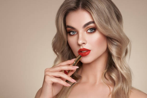 istock A beautiful young blonde woman applying lipstick 1369110145