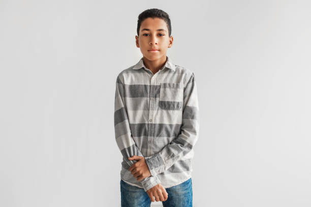 Serious Black Preteen Boy Looking At Camera Over Gray Background