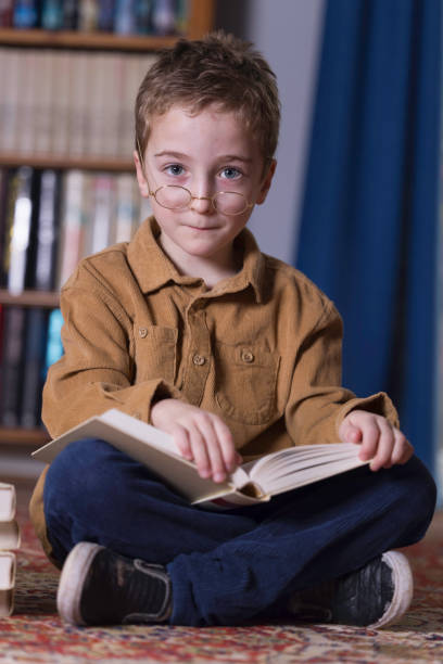 7-year-old boy sitting on the floor reading a book.