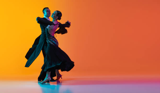 volante con pareja de baile, hermoso hombre y mujer bailando vals aislado sobre fondo rosa naranja degradado en luz de neón. concepto de belleza, arte, deporte - tango fotografías e imágenes de stock