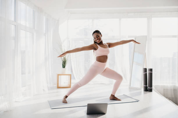 istock Joyful fit young black woman practicing yoga at home, standing in warrior pose, copy space 1369113786