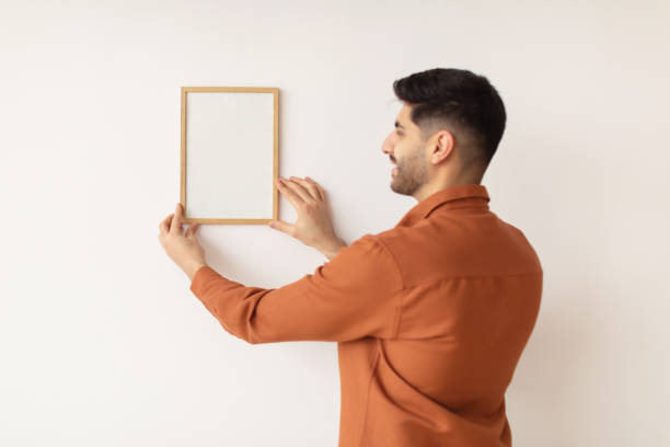 istock Young man hanging picture frame on the wall 1369113866
