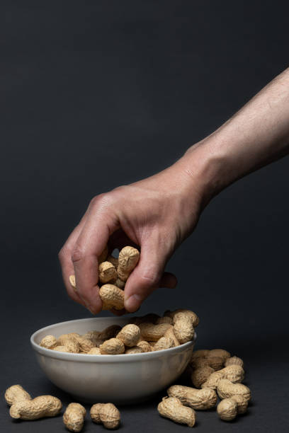 istock Man hand picking unpeeled peanuts from a bowl 1369118452