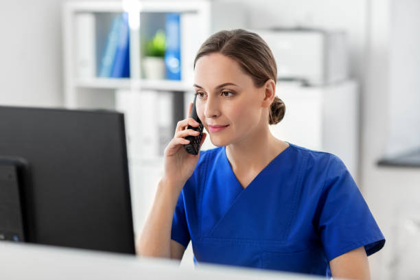 medico con chiamata al computer al telefono in ospedale - receptionist foto e immagini stock