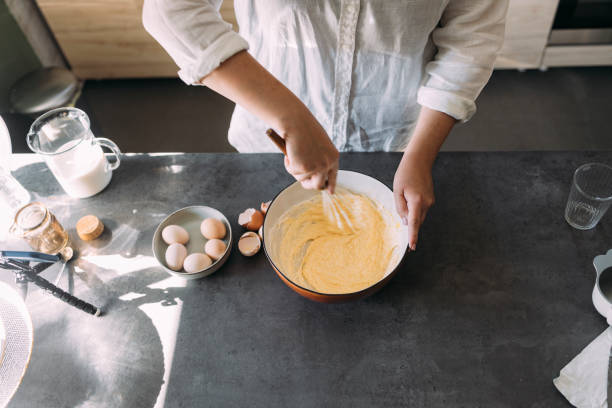 istock Anonymous Plus Size Female Baker Mixing Dough with a Whisk in a Domestic Kitchen 1369118964