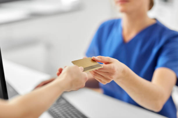 patient giving doctor credit card at hospital medicine, people and healthcare concept - close up of patient giving female doctor or nurse insurance or credit card card at hospital health insurance stock pictures, royalty-free photos & images