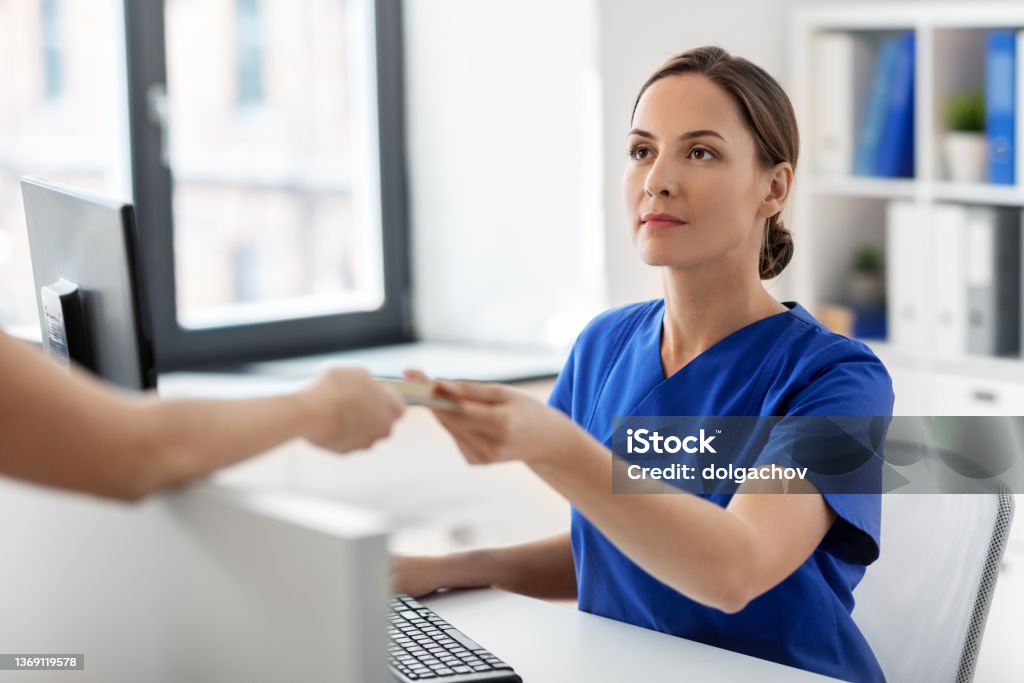 doctor and patient with credit card at hospital medicine, people and healthcare concept - female doctor or nurse and patient with insurance or credit card card at hospital Paying Stock Photo