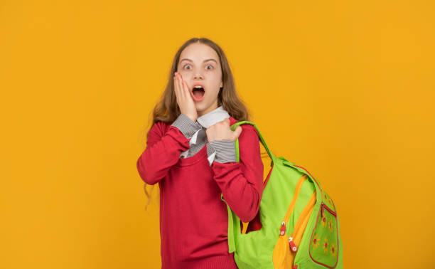 istock amazed kid with school backpack on yellow background, school 1369120261