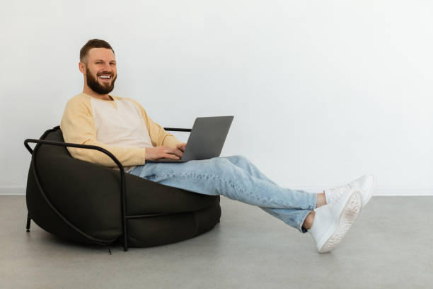 istock Successful Freelancer Man Using Laptop Working Sitting In Chair Indoors 1369122057