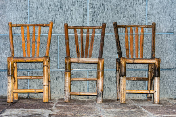 istock Three Chinese bamboo chairs against a stone wall. 1369124299