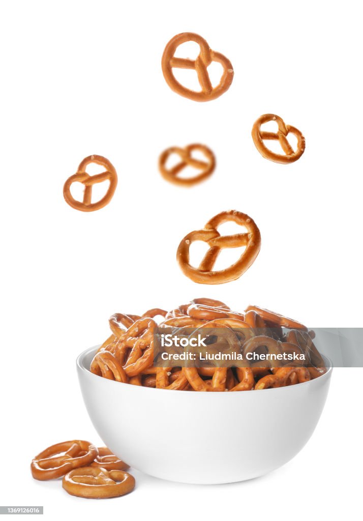 Tasty crispy pretzel crackers falling into bowl on white background Pretzel Stock Photo