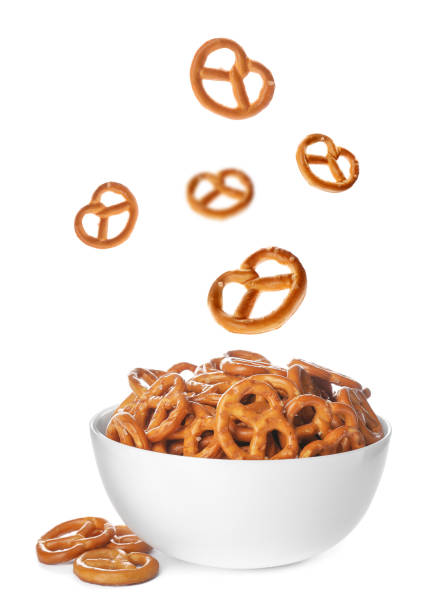 tasty crispy pretzel crackers falling into bowl on white background - pretzel imagens e fotografias de stock
