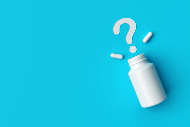 istock Plastic medical container and white capsule pills with question mark on blue background top view. 1369127041
