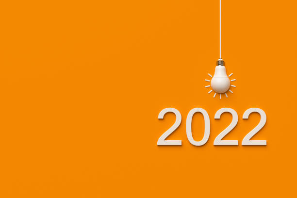 istock 2022 and white light bulb on orange background. 1369127064