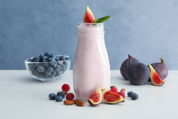 istock Delicious fig smoothie in glass bottle on white table 1369128178