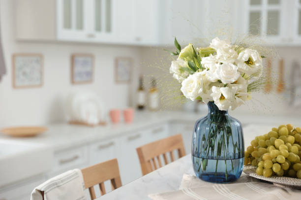 istock Bouquet of beautiful eustoma flowers and grapes on white table in kitchen. Interior design 1369128277
