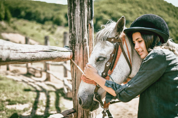 istock Cute Female Jockey Calming Her Mare Down On Ranch 1369128835