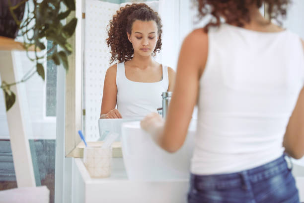 istock Sad teenager looking in the mirror 1369129339