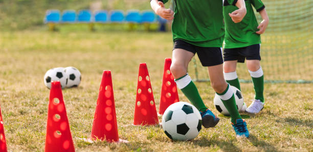 crianças que frequentam o treinamento de futebol no campo escolar. jovem treinando crianças em aula de educação física. prática de futebol para crianças - junior high fotos - fotografias e filmes do acervo