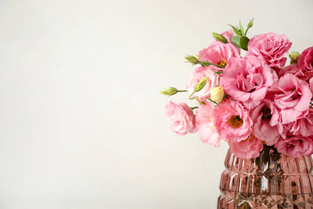 istock Beautiful pink Eustoma flowers in vase on light background. Space for text 1369129559