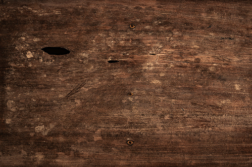Natural wood texture. Close-up shot of natural dark brown wood board, weathered, scratched, distressed.