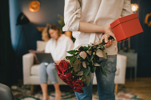 Young man giving present to his girlfriend at home. Valentine's Day celebration.